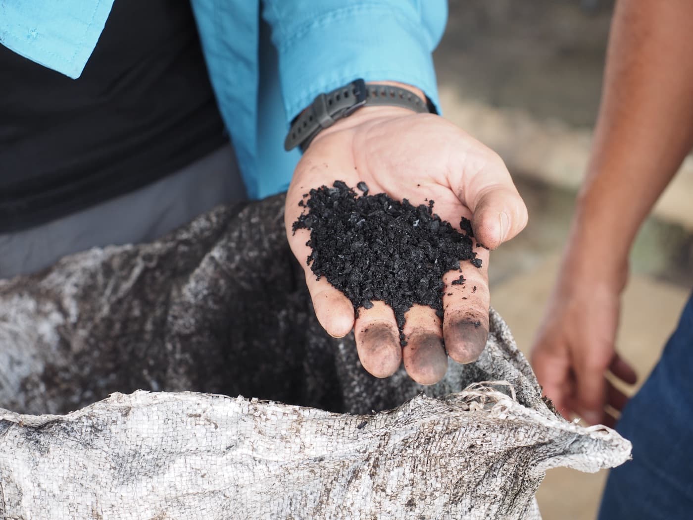 A handful of finished biochar pulled from a bag at a smallholder site